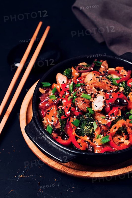 Asian cuisine, teriyaki meat with vegetables, in a cast-iron frying pan, close-up, no people