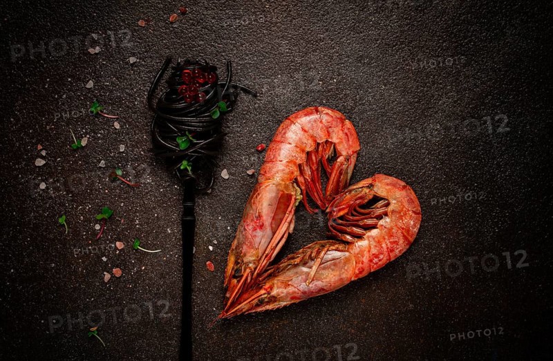 Black spaghetti, wrapped on a fork, langoustines in the shape of a heart, on the table, dish concept, dish background, top view