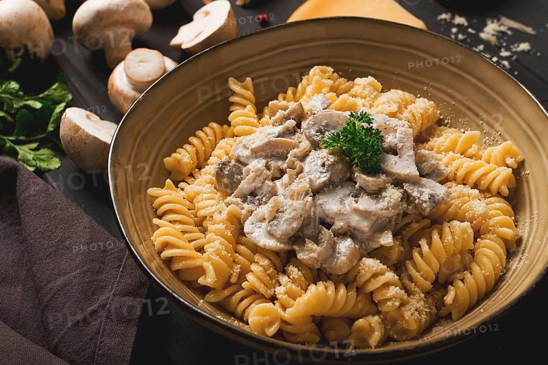 Fusilli pasta, with champignons in cream sauce, top view, with ingredients, on a wooden table, no people