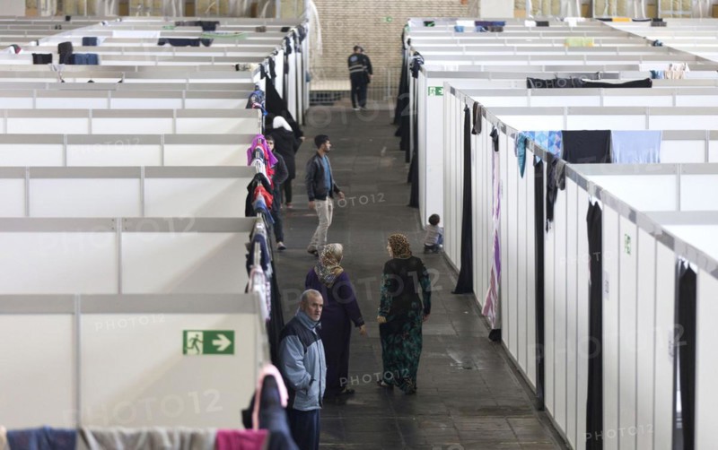Children of refugees look over the wall of a temporary room in an emergency shelter for refugees on 9 December 2015 in the former hangar of Tempelhof Airport, Berlin, Berlin, Germany, Europe