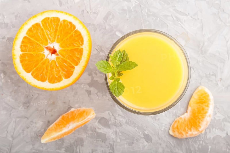 Glass of orange juice on a gray concrete background. Morninig, spring, healthy drink concept. Top view, close up, flat lay
