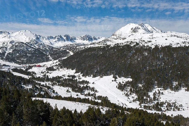 Winterliche Berglandschaft mit schneebedeckten Bergen, dicht bewaldeten Hängen und blauem Himmel mit Wolken, Blick auf das Skigebiet Grau Roig, Pyrénées-Orientales, Encamp, Fürstentum Andorra, Pyrenäen