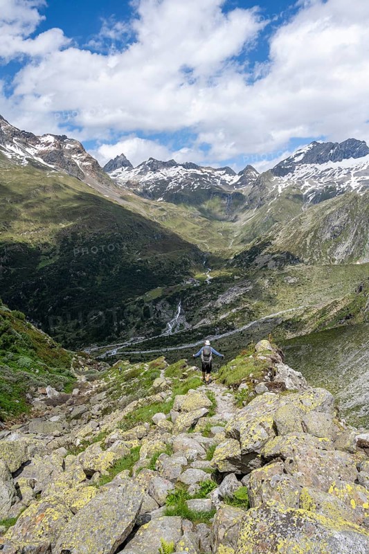 Mountaineer on hiking trail in front of picturesque mountain landscape, rocky mountain peaks with snow, valley Zemmgrund with Zemmbach, mountain panorama with summit Großer Mörchner and Zsigmondyspitze, Berliner Höhenweg, Zillertal Alps, Tyrol, Austria, Europe