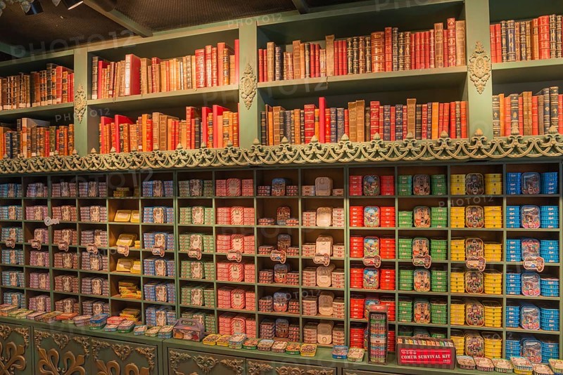 Wall of shelves with books on top and numerous colourful tins underneath, tins of sardines, tinned sardines, Óbidos, Obidos, Oeste, Centro, Estremadura, Portugal, Europe