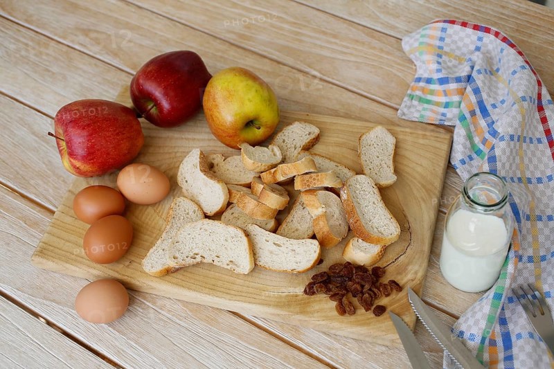 Swabian cuisine, ingredients for Ofenschlupfer, sweet main course or dessert, dessert, sweet dish, typical Swabian, classic, from the oven, casserole, leftovers, stale bread rolls, sultanas, apples, eggs, cream, milk, arranged on wooden board, home cooking, traditional cuisine, food photography, studio, Germany, Europe