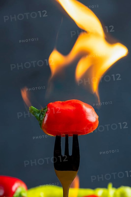 Burning red pepperoni on a fork, close-up, food photography