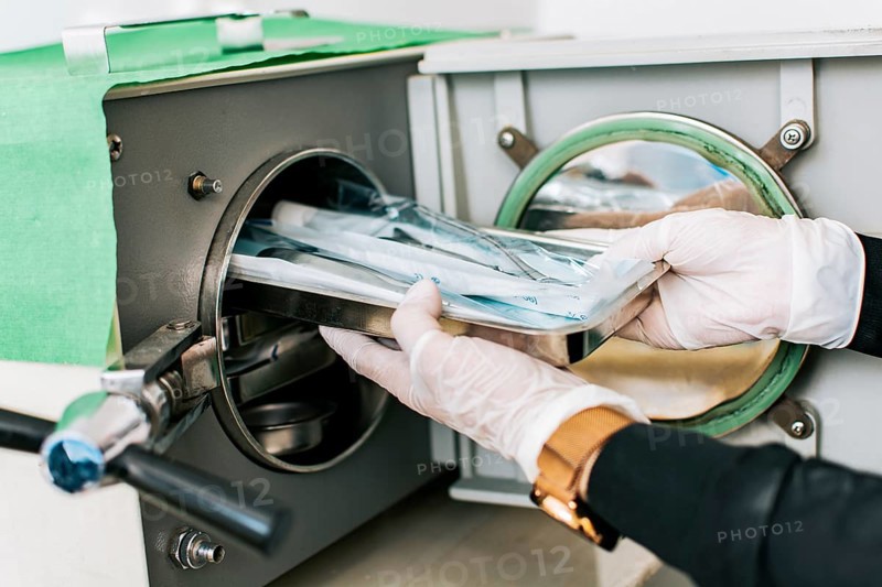A dentist sterilizing his tools, Dentist with a dental sterilizer, A dentist with a dental autoclave, Close up of a dentist with a steam sterilizer