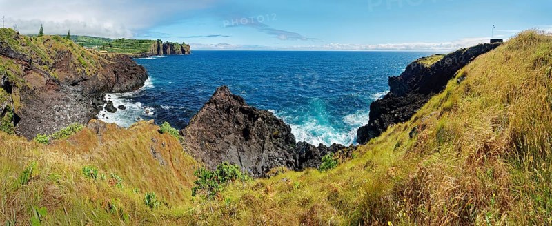 Panorama of a rocky coastal view with rugged cliffs plunging into the blue sea under a clear sky, Capelas, Sao Miguel Island, Azores, Portugal, Europe
