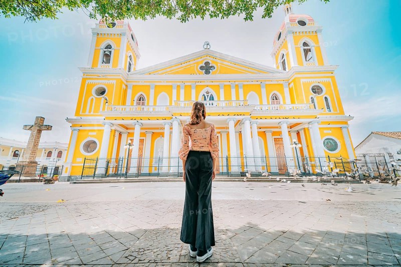 Rear view of a tourist woman in front of a cathedral in a tourist square. Back view of a beautiful tourist in the tourist plaza of Granada, Nicaragua, Central America