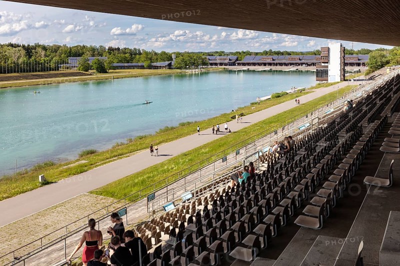 View from the grandstand of a lake with paddlers, surrounded by a natural landscape, Oberschleißheim regatta course