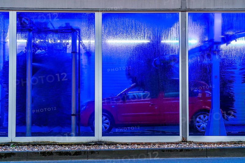 Car in an automatic car wash, car wash tunnel, cleaning foam is sprayed on, rotating brushes clean the vehicle