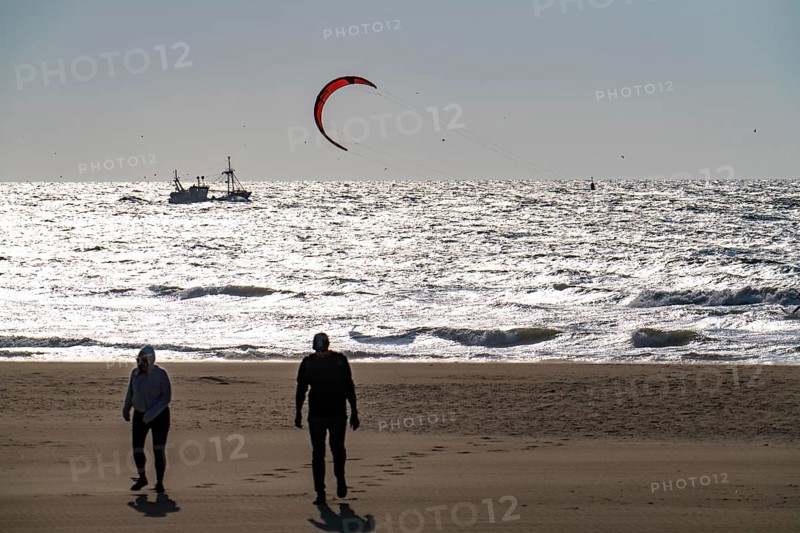 Kitesurfers and shrimp boats off the coast of Scheveningen, walkers on the beach, The Hague, Netherlands