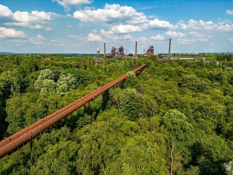 The Duisburg Nord Landscape Park, double blast furnace gas pipeline from the west View across the wilderness, a park area where nature is left to its own devices, to the steelworks, North Rhine-Westphalia, Germany, Europe