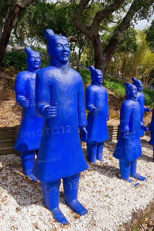 A group of blue terracotta warrior statues stands on gravel, surrounded by trees, Bacalhôa, Bacalhoa Buddha Eden, Quinta dos Loridos, largest oriental garden in Europe, Bombarral, Oeste, Centro, Portugal, Europe