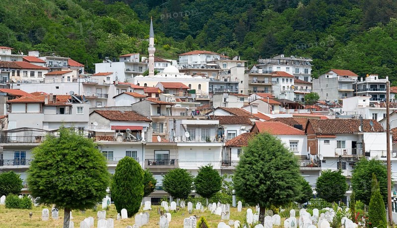 A dense settlement with a minaret nestled against a wooded hill with a cemetery in the foreground, Echinos, centre of the Pomaks, Myki, Xanthi, Eastern Macedonia and Thrace, Greece, Europe