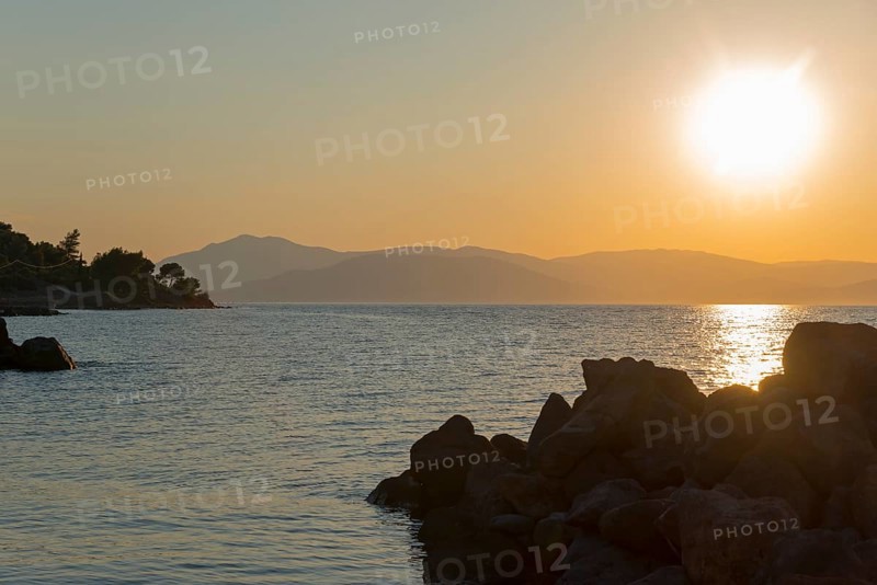 Sunset over the sea, silhouettes of rocks and mountains, warm colours, Agíos Nikólaos, Agios Nikolaos, Methana peninsula, regional district of Argolida, Argolis, Peloponnese, Greece, Europe