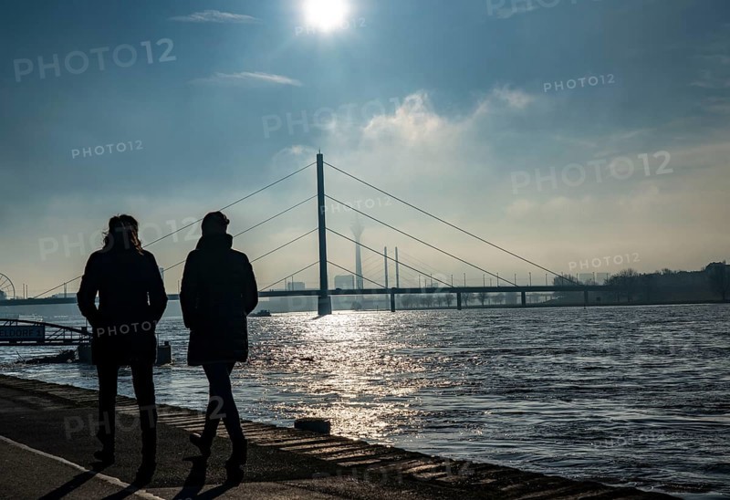 Dense fog is slowly lifting, riverside promenade on the Rhine near Düsseldorf, in front the Oberkassler Bridge, behind it the Rheinknie Bridge, North Rhine-Westphalia, Germany, Europe