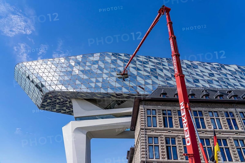 The Antwerp Port Authority building, Havenhuis, former fire brigade barracks in the harbour, renovated and with an attached glass structure, in the shape of a ship's hull, administrative headquarters of the Antwerp Port Authority, designed by Zaha Hadid, building cleaners clean the windows, truck work platform of the German rental company Gerken, Antwerp, Flanders, Belgium, Europe