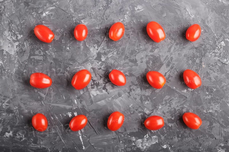 Rows of cherry tomatoes on a black concrete background, top view, flat lay