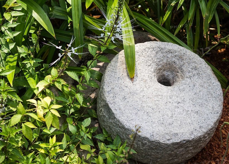 Decorative gray millstone in a botanical garden
