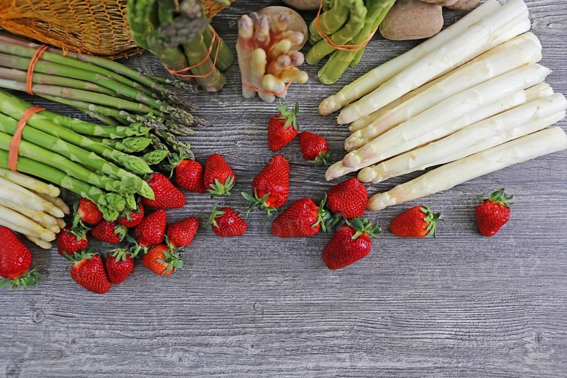 Green asparagus, white asparagus and fresh strawberries decorated on a rustic wooden table