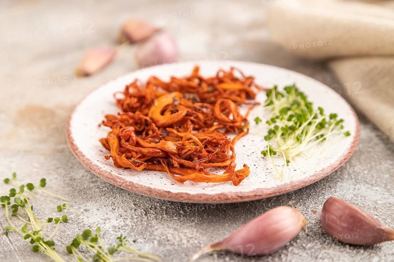 Fried Cordyceps militaris mushrooms on brown concrete background with microgreen, herbs and spices. Side view, copy space, selective focus