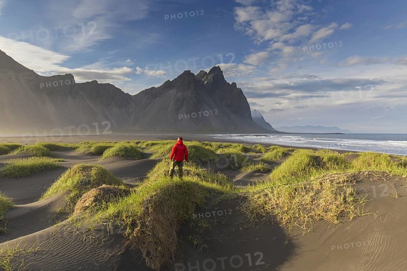 Hiker looking over the Vestrahorn, Vesturhorn, made of gabbro and granophyre rocks, part of the Klifatindur mountain range at Stokksnes, Iceland, Europe