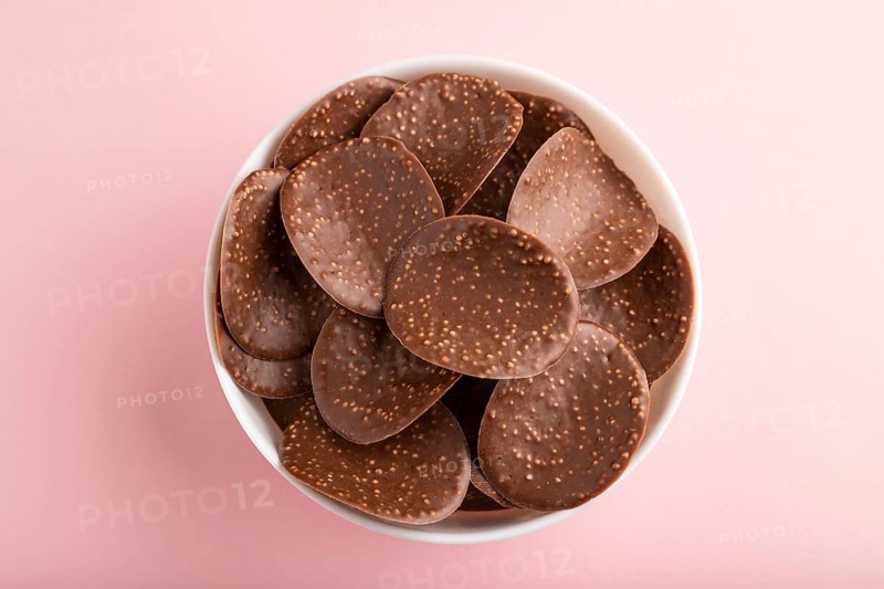 Chocolate chips with caramel on pink pastel background. top view, flat lay, close up