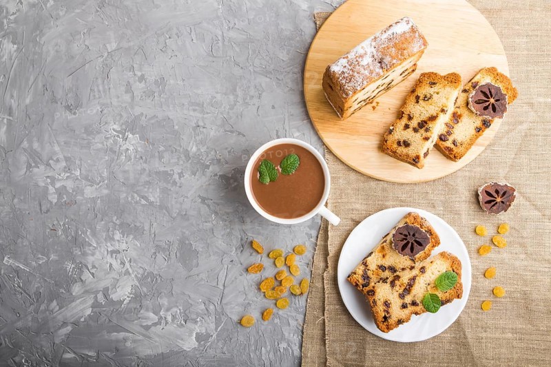 Homemade cake with raisins, dried persimmon and a cup of hot chocolate on a gray concrete background and linen textile. top view, flat lay, copy space