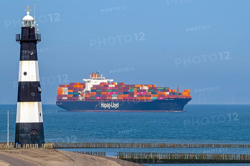 Container ship, containership Hudson Express of the Hapag-Lloyd AG shipping company sailing on the Western Scheldt past the Breskens lighthouse