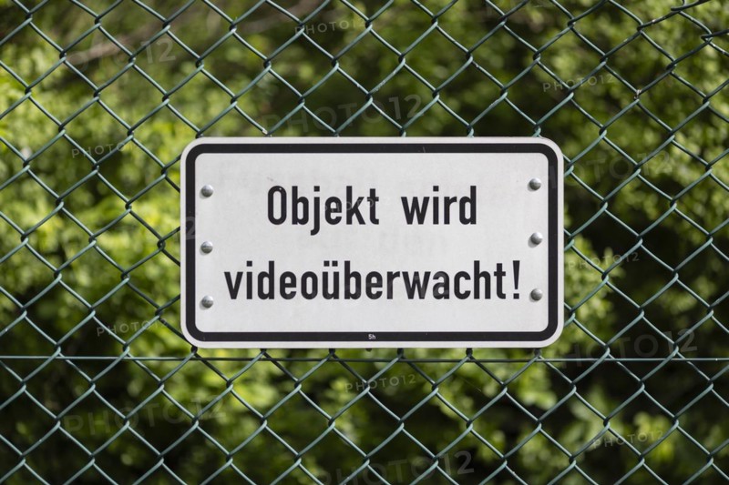 Sign mounted on a green wire mesh fence with the inscription: Objekt wird videoüberwacht! in Berlin, 08/04/2024