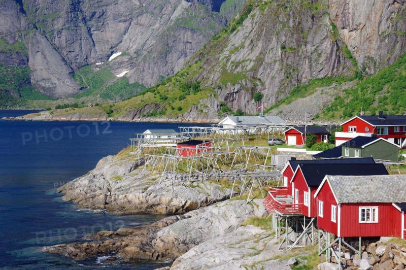 Red rorbu houses on rocks and high, rugged, mountains, holiday, holiday homes Hamnoy, Lofoten, Nordland