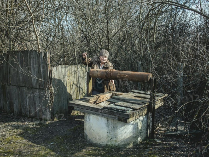 Larisa draws water from a well in Borshchivka. The village was under Russian occupation. She hid with her granddaughter Angelina in her house for almost six months, Borshchivka, Raion Isyum, Kharkiv Oblast, Ukraine, Europe