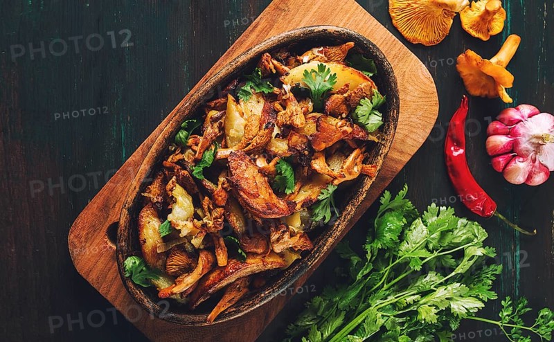 Fried chanterelles with mushrooms, in a clay pan, close-up, top view, selective focus