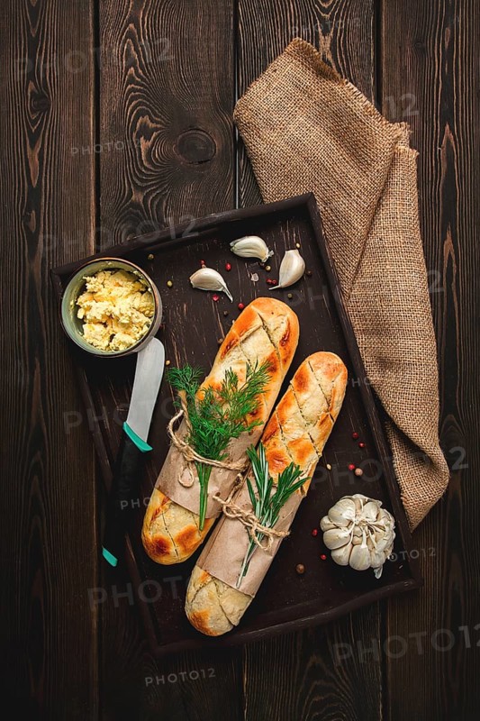 Baguette with garlic butter and herbs, fried, on a brown wooden table, top view, rustic style, no people