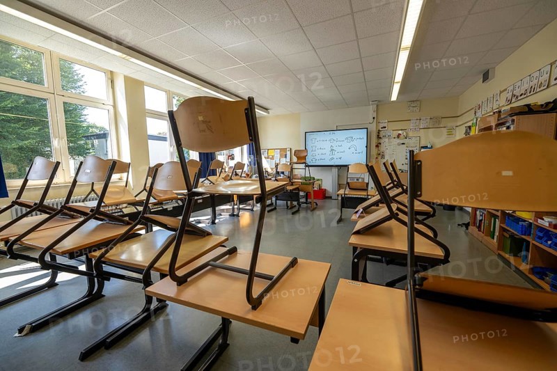Classroom of a fourth grade, after school, the building is older but in good condition, modern teaching materials, interactive, digital whiteboard