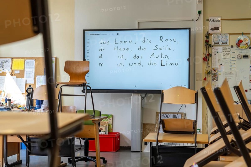 Classroom of a fourth grade, after school, the building is older but in good condition, modern teaching materials, interactive, digital whiteboard