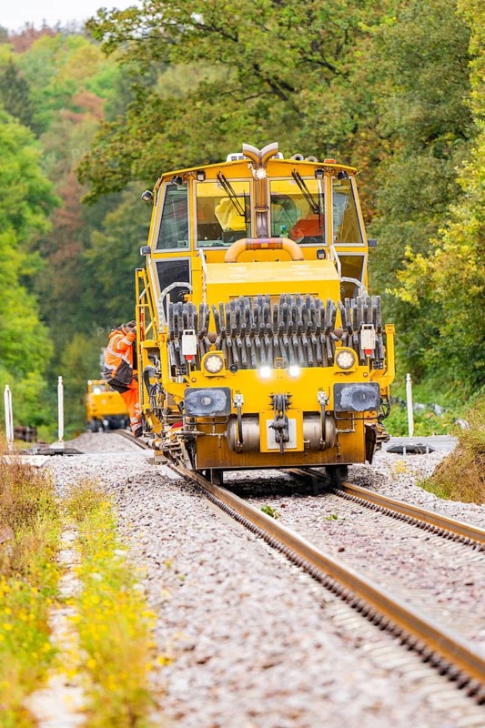 Yellow tractor moving on a railway track through a densely wooded area, Hermann Hesse Bahn track construction, Calw district, Black Forest, Germany, Europe