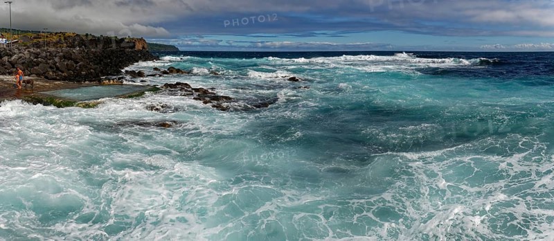Stormy waves crash against a rocky shore under a cloudy sky, seawater bathing establishment, Capelas, Sao Miguel Island, Azores, Portugal, Europe