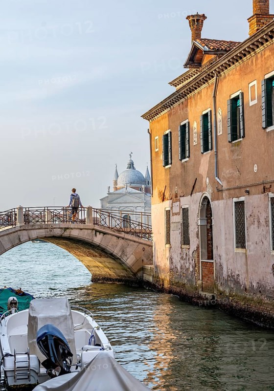 Young man standing on a bridge over a canal, behind the church Chiesa del Santissimo Redentore, Venice, Veneto, Italy, Europe