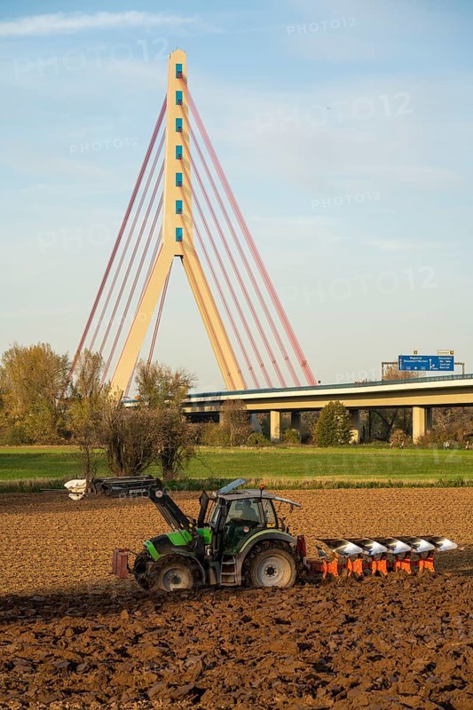 Farmer ploughing a field, tractor with plough, near Neuss, Fleher motorway bridge, A46, North Rhine-Westphalia, Germany, Europe