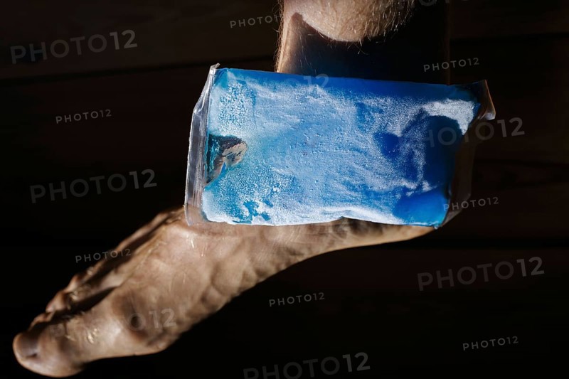 Symbolic photo on the subject of cooling for joint pain. A cooling pad is placed on an ankle and cools the joint. Berlin, 21.08.2024
