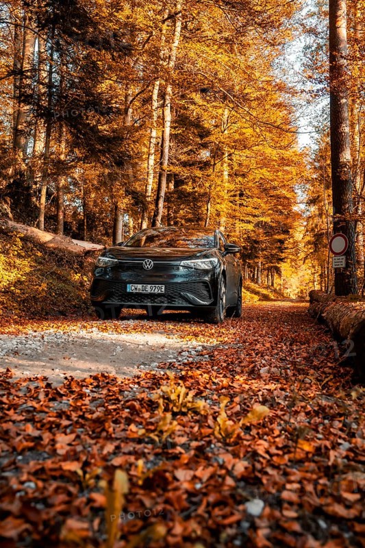 Car on autumnal forest road with orange leaves, electric car VW ID5, Gechingen, Black Forest, Germany, Europe