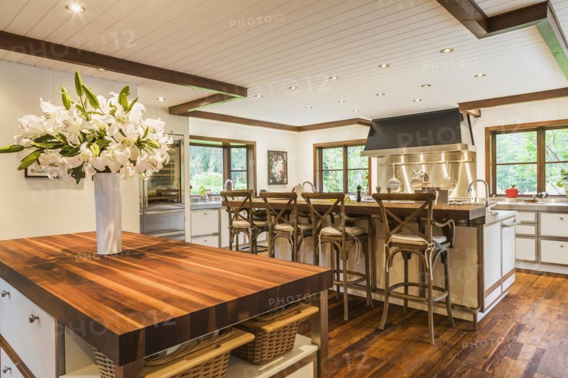 Country style kitchen with island and rustic wooden high chairs inside a New Hampton style home, Quebec, Canada, North America