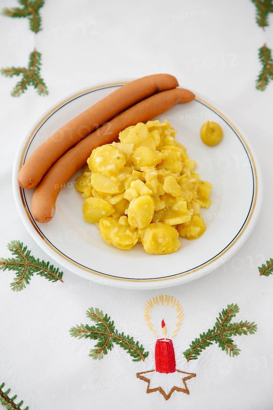 Swabian cuisine, potato salad with string sausages, Wienerle, Wiener sausages, thin boiled sausage, horseradish sausage, Frankfurter sausage, savoury, salty, typical Swabian, typical Christmas dinner, fast food for Christmas Eve, home cooking, plate, mustard, Christmas decoration, hand-embroidered table linen, Christmas motifs, fir branch motif, Christmas tablecloth, handmade, embroidered candle, traditional cuisine, food photography, studio, Germany, Europe