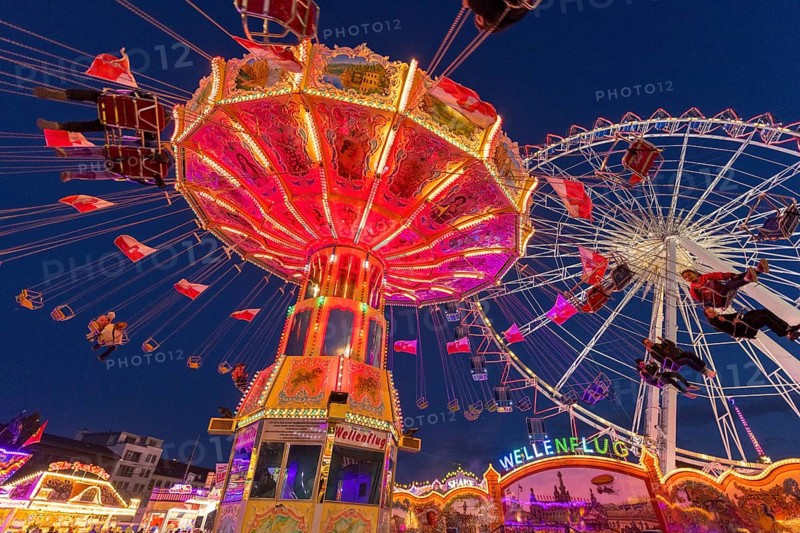 A funfair at dusk with illuminated chain carousel and Ferris wheel, Europa Rad, rides, wave flight, Cannstatter Wasen, folk festival, Bad Cannstatt, Stuttgart, Baden-Württemberg, Germany, Europe