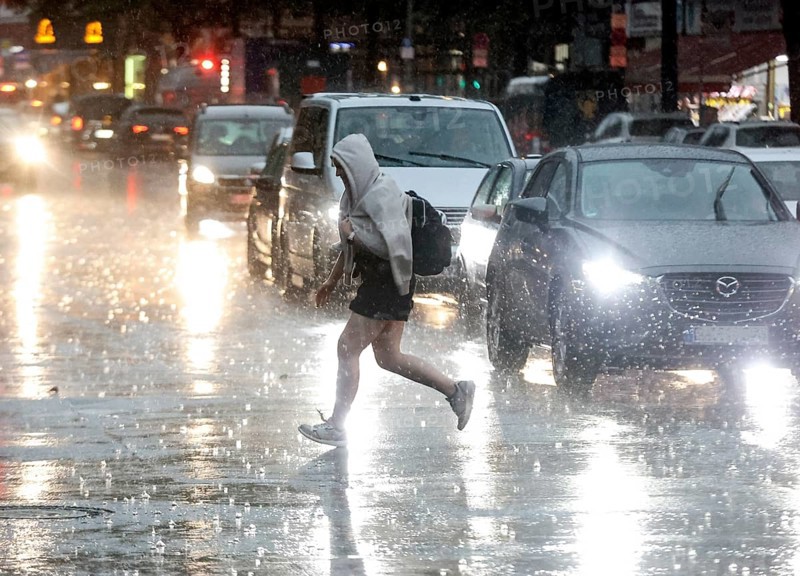 People try to protect themselves from the rain on Potsdamer Strasse. After weeks of heat, the first heavy rain brought cooling, Berlin, 15.08.2022