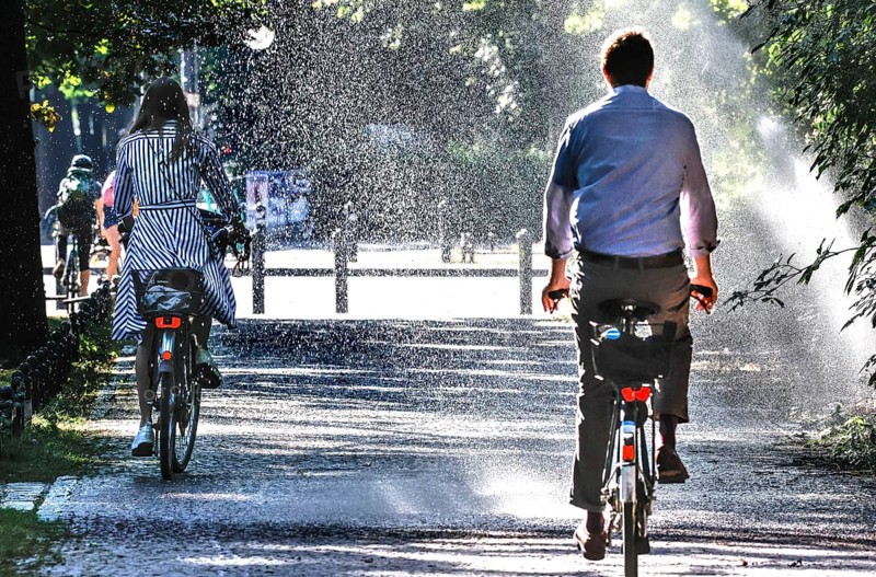 A cyclist cools down with a lawn sprinkler in Berlin's Tiergarten, 03/08/2022