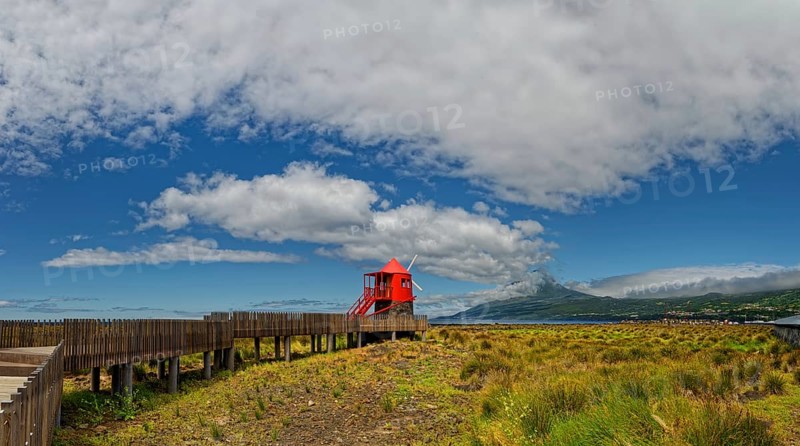 Wooden path leads to the Moinho das Lajes windmill with a dramatic sky and the volcanic cone of Pico in the background, fishing village, Lajes do Pico, Lajes, Pico Island, Azores, Portugal, Europe