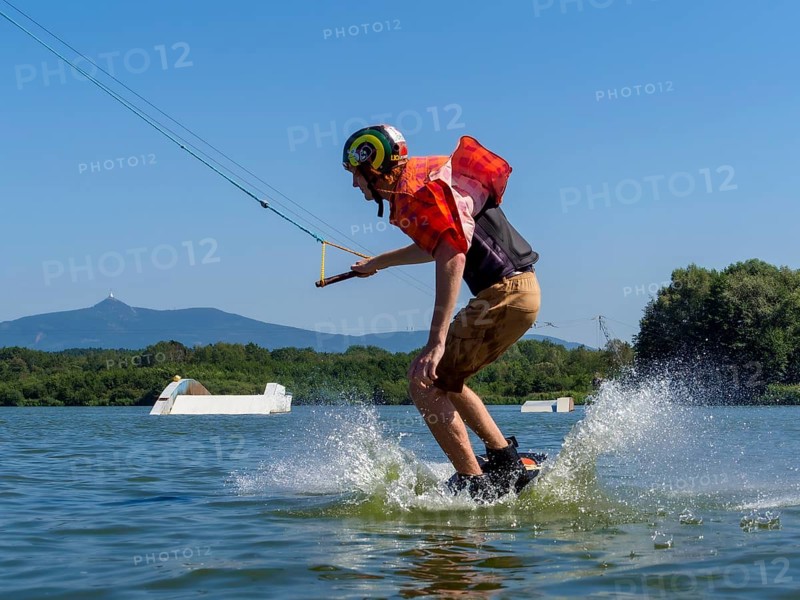 Young casual man with flapping shirt on wakeboard jumping into the lake, water ski and wakepark, Stráž pod Ralskem, Czech Republic, Europe